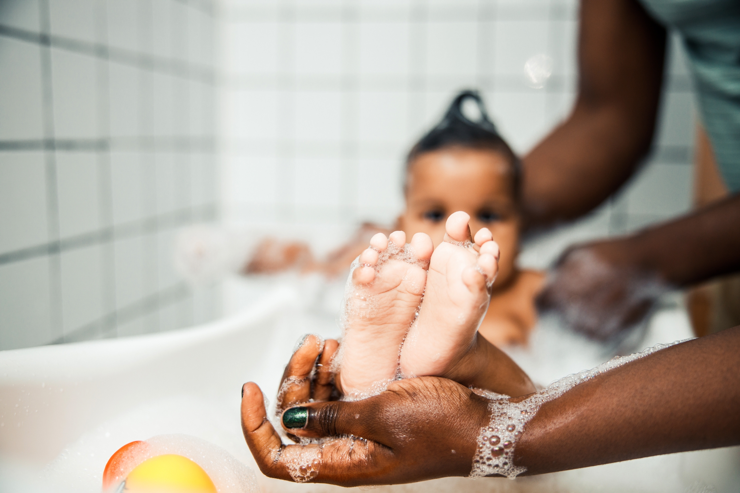 Cover image of baby getting a bath from parents.