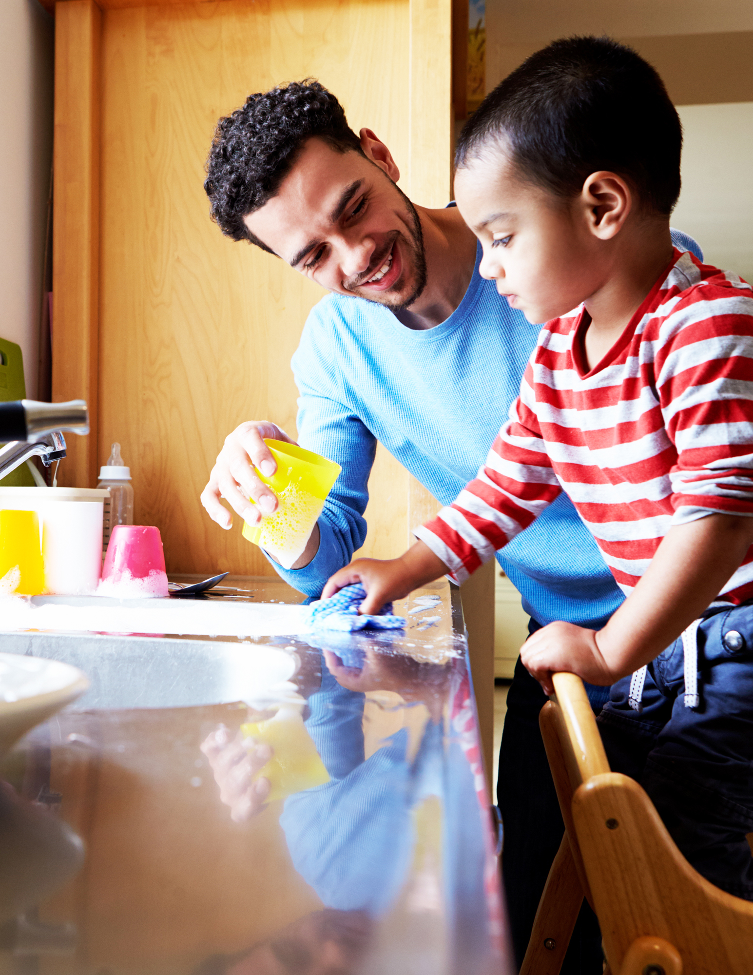 Parent and child washing dishes together at the sink